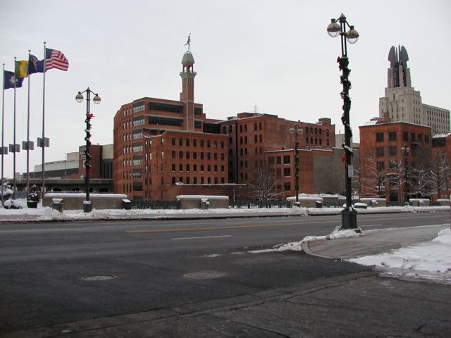 Picture Main St Bridge flags fly in front of convention center, snow covered bridge rails, statue of Mercury and Times building highlight the skyline view. Rochester NY New York City living January 11th 2003 POD I Love NY Rochester NY New York Picture Of The Day view picture photo image pictures photos images, January 11th 2003 POD