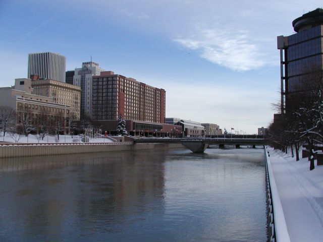 Picture Genesee River looking south from the west bank, Rochester Chamber Of Commerce, Four Points Sheraton, Lincoln Tower, Hyatt Hotel, Convention Center, and Rundell Library on left . Snow covered landscape and the old revolving restaraunt on the right side. Rochester NY New York City living January 15th 2003 POD I Love NY Rochester NY New York Picture Of The Day view picture photo image pictures photos images, January 15th 2003 POD